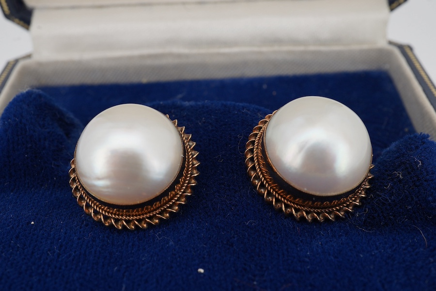 A pair of yellow metal and mabe pearl set ear clips, with rope twist borders, diameter 16mm, gross weight 7.6 grams. Condition - fair to good